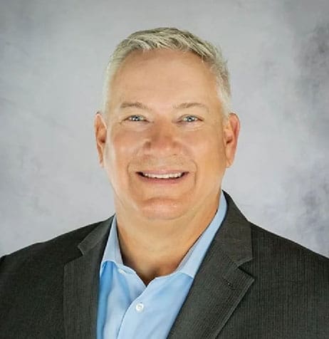 A man in a suit and tie smiling for the camera.