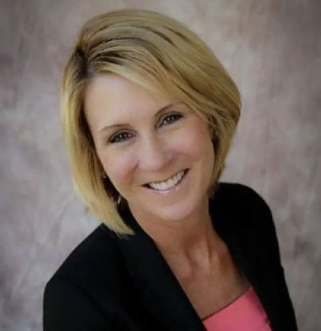 A woman with blonde hair and pink shirt smiling.