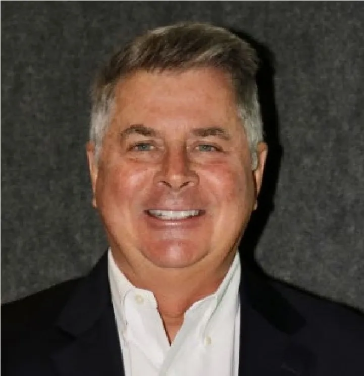 A man in a suit and tie smiling for the camera.