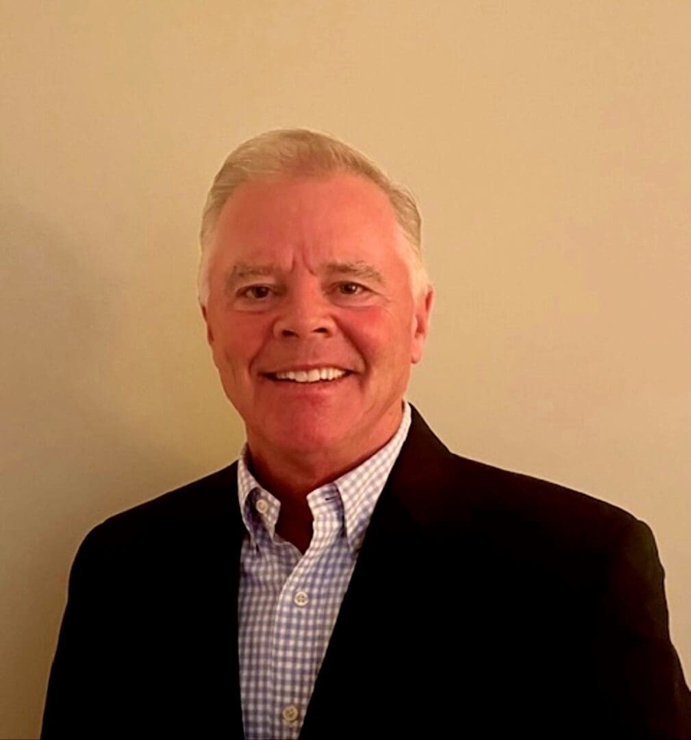 A man in a suit and tie smiling for the camera.